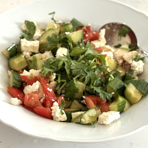 Cucumber salad with tomatoes, feta, and coriander, dressed in olive oil and balsamic vinegar.